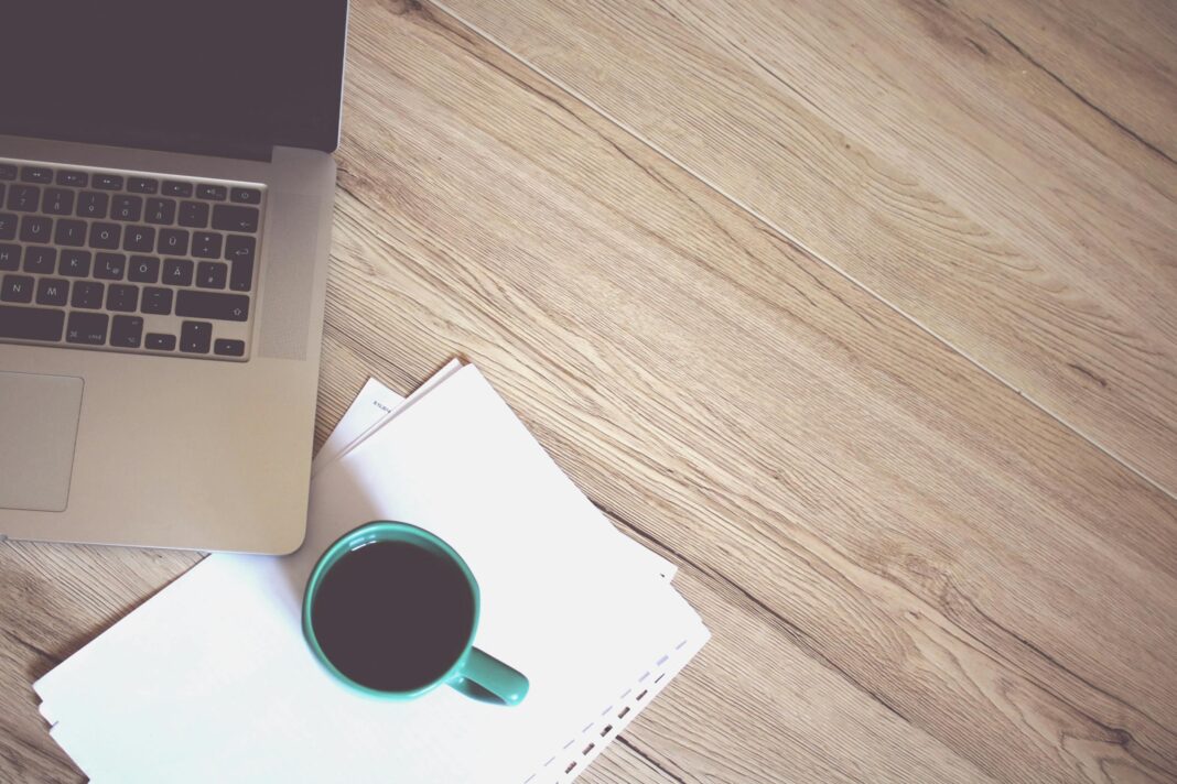 Laptop with coffee mug on a wooden desk, representing a blogger’s workspace.